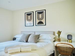 法恩伯勒Luxurious Detached Bungalow with Private Parking的卧室配有一张白色床,墙上挂有两张照片