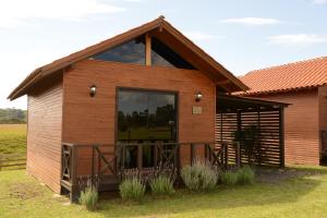 圣若阿金Pousada Querência Tarumã的木质小屋,设有田野上的大窗户