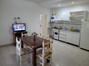 林肯"La Irma" - Complejo de Departamentos的厨房配有木桌、椅子和电视