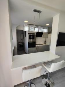 贝尼多姆Apartamento Costa de Poniente的厨房配有白色的柜台和白色的椅子