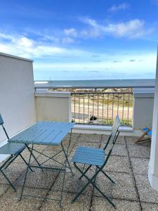 滨海苏拉克Appartement vue mer的海景阳台上摆放着一张蓝色的桌子和两把椅子