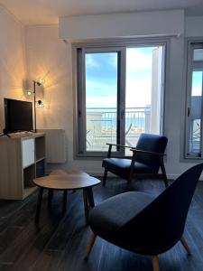 滨海苏拉克Appartement vue mer的客厅配有椅子、桌子和电视