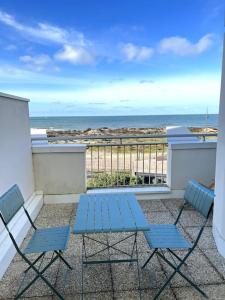 滨海苏拉克Appartement vue mer的海滩阳台配有2把蓝色椅子和1张桌子