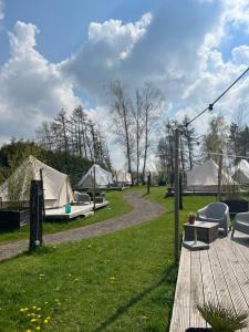 BlesdijkeGlamplodge met privé sanitair的一组帐篷位于带木甲板的田野中