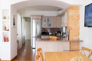 爱琴娜岛Naias Aegina, Sea-front apartment 95 sqm的厨房配有白色橱柜和木桌