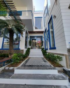 绥和市Alicia Hotel的一座带蓝色门和棕榈树的房子