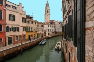 威尼斯Cà Regina Panada - passion on the Canal的一条城市的运河,里面装有船只