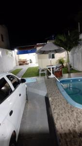 阿拉卡茹CASA DE TEMPORADA RECANTO FELIz 2的夜间在游泳池旁停放的白色汽车