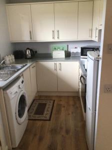 肯德尔Birslack Grange的厨房配有白色橱柜和洗衣机。