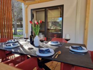 德拉格Premium mobile home SUN & JOY - Oaza Mira Camping的一张带红椅子和酒杯的黑桌