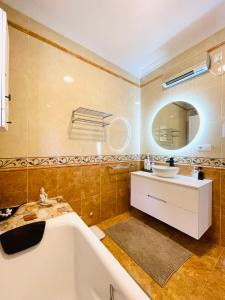 比纽埃拉Villa Casira met 2 studio's - 10 personen, Viñuela, Costa Del Sol的带浴缸、水槽和镜子的浴室
