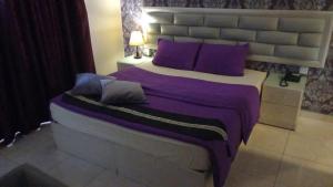 安曼Beirut Hotel 1的一间卧室配有一张带紫色枕头的大床
