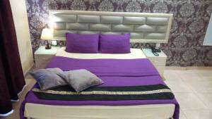 安曼Beirut Hotel 1的一间卧室配有一张带紫色枕头的大床