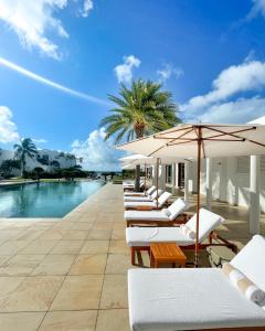 EbenezerAurora Anguilla Resort & Golf Club的游泳池旁一排带遮阳伞的躺椅