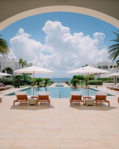 EbenezerAurora Anguilla Resort & Golf Club的度假村的游泳池,配有椅子和遮阳伞