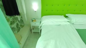 伊斯基亚Hotel Casa Nicola的小型客房的两张床,设有绿色的墙壁