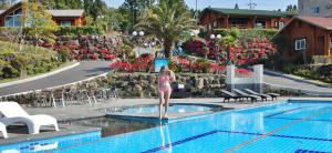 西归浦市济州我有酒店度假村 的站在游泳池旁的比基尼的女人