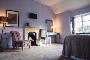 WedmoreThe George Inn Wedmore的一间卧室设有壁炉、一张床和一把椅子