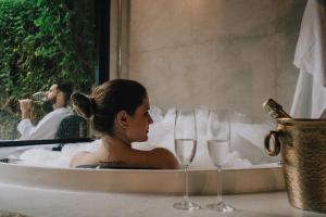 蒙特韦尔迪LaPianta的坐在浴缸里,戴着两杯酒杯的女人