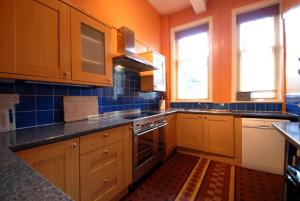 康威Berthlwyd Hall的厨房配有木制橱柜和炉灶烤箱。