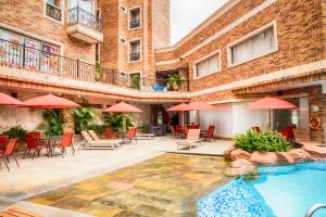 巴兰基亚巴兰基亚温莎酒店的酒店庭院设有游泳池、桌子和遮阳伞。