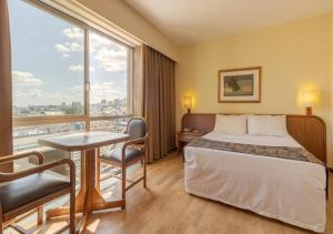阿雷格里港Ritter Hotéis的配有一张床、一张书桌和一扇窗户的酒店客房