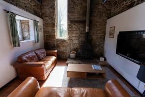 PaulBeautiful Cornish barn in the stunning Lamorna valley with large garden的客厅配有皮革家具和平面电视