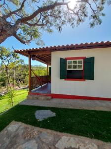 迪亚曼蒂纳Chalés Vila das Cachoeiras的一间白色的小房子,设有红色和绿色的窗户