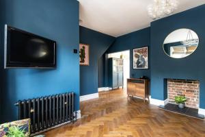 波茨莱德Newly renovated Victorian house with free parking的客厅设有蓝色的墙壁和平面电视。
