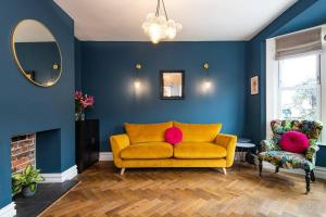 波茨莱德Newly renovated Victorian house with free parking的蓝色客厅里的黄色沙发,配有镜子