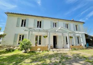 HostensEntre Chênes et Pins - Gîte de groupe 3 étoiles的一座带庭院的大型白色房屋