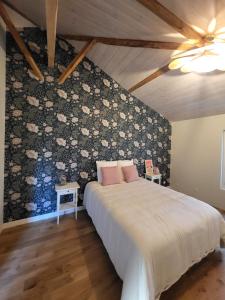 HostensEntre Chênes et Pins - Gîte de groupe 3 étoiles的一间卧室配有一张带花卉图案墙壁的床