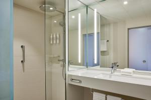 美因河畔法兰克福法兰克福艾美度假酒店的一间带水槽和玻璃淋浴的浴室