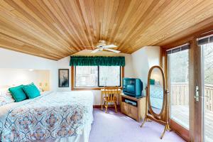 卡农海滩Cannon Beach Cottage的一间卧室配有一张带吊扇的床和一台电视。