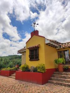 FúqueneCasa Finca El Mirador frente a la laguna de Fúquene的上面有十字架的黄色和红色小房子