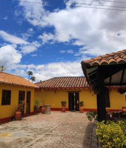 FúqueneCasa Finca El Mirador frente a la laguna de Fúquene的黄色的建筑,设有瓷砖屋顶和庭院