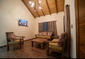 哈拉瓦科阿VillaLunaCaridad的客厅配有椅子、桌子和电视