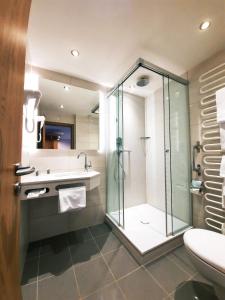 柯尼希斯湖畔舍瑙布鲁奈克阿本酒店的一间带玻璃淋浴和水槽的浴室