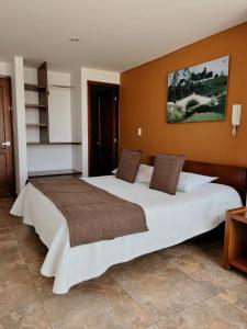 杜伊塔马Hotel Milán的橙色墙壁的房间里一张大白色的床
