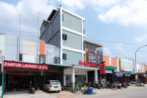 秾莎RedDoorz near Hang Nadim Batam Airport的街道边的建筑物,前面有车辆停放