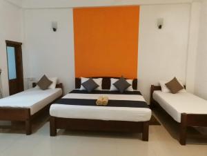 蒂瑟默哈拉默The Yala City Guest House的一间卧室设有两张床,墙壁上装饰有橙色和白色