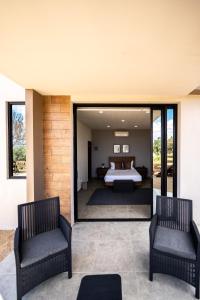 瓜达鲁佩镇Villa Sophia Valle de Guadalupe的一间卧室配有一张床和两把椅子
