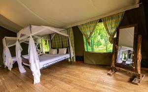 恩戈罗恩戈罗恩戈罗恩戈罗野营豪华帐篷的一间卧室配有天蓬床和镜子