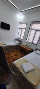 布哈拉KAMIR Guest House的客房设有两张床、一张桌子和两个窗户。