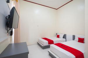 SolokRedDoorz Syariah near RS Tentara Solok的客房设有两张床、一台电视和一张书桌。