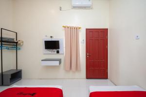 SolokRedDoorz Syariah near RS Tentara Solok的一间带红色门和电视的客厅