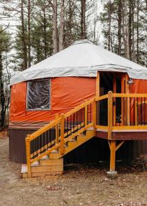 彭延Heated & AC Yurt的橙色蒙古包,在树林里设有门廊和楼梯