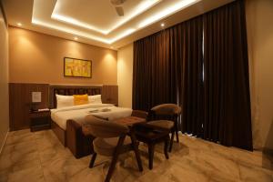 大诺伊达Lime Tree Hotel and Banquet Greater Noida的酒店客房带一张床、一张桌子和椅子