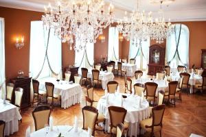 热莱胡夫热莱胡夫宫温泉疗养酒店的用餐室配有白色桌椅和吊灯。