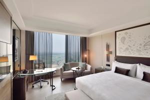 加尔各答加尔各答JW万豪酒店的酒店客房,配有一张床、一张桌子和椅子